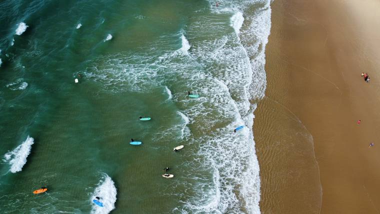 Vagues et surfeurs le long d'une plage de l'Atlantique, vue par drone